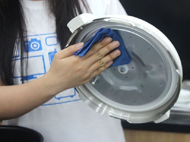 Sử dụng mảnh vải mềm thấm ẩm để lau sạch nắp nồi Sử dụng mảnh vải mềm thấm ẩm để lau sạch nắp nồi